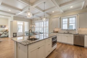 Open concept kitchen and living room with coffered ceilings and hanging pendant lights