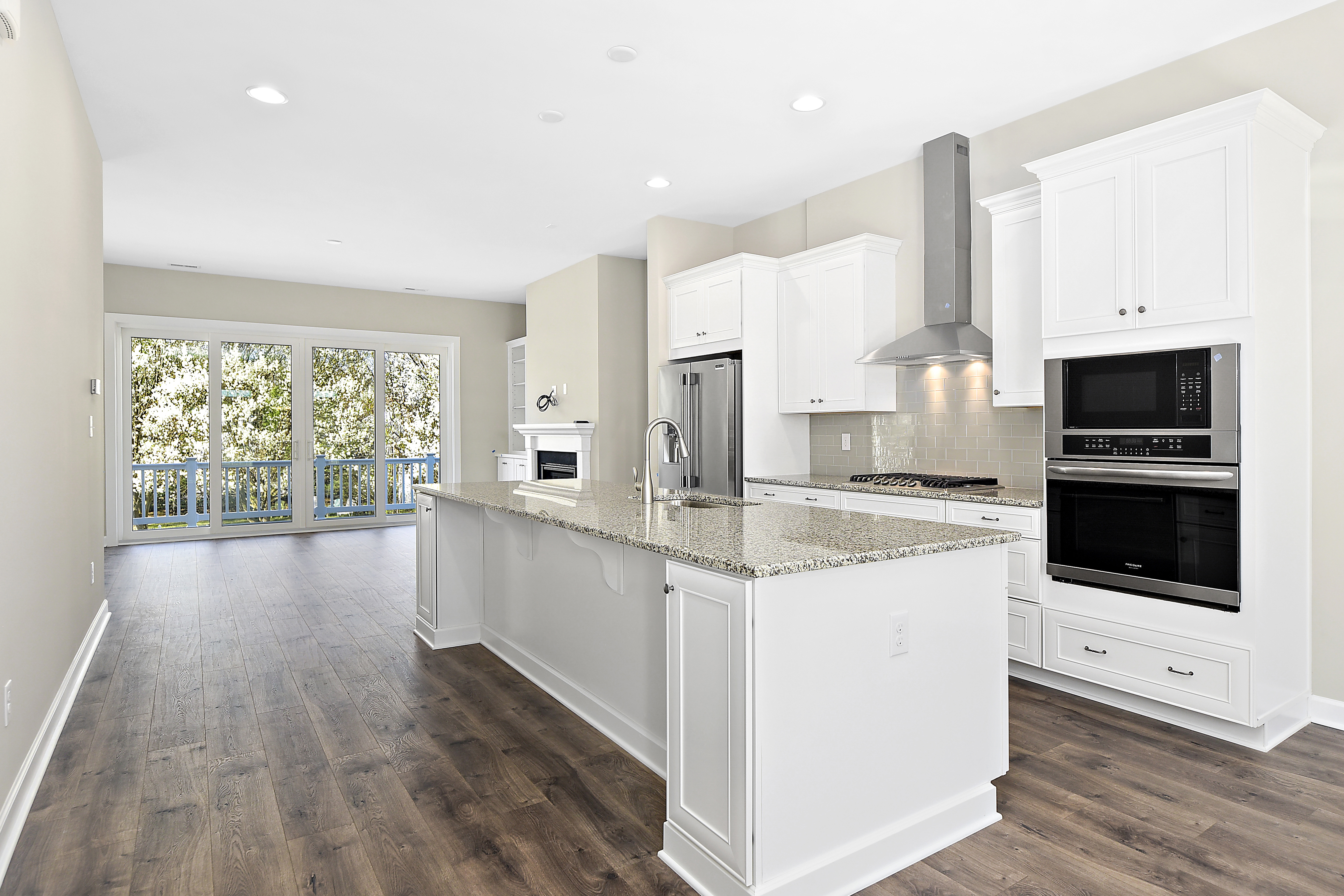 Large kitchen island in open floorplan of Turnstone home, with white cabinets and hardwood flooring