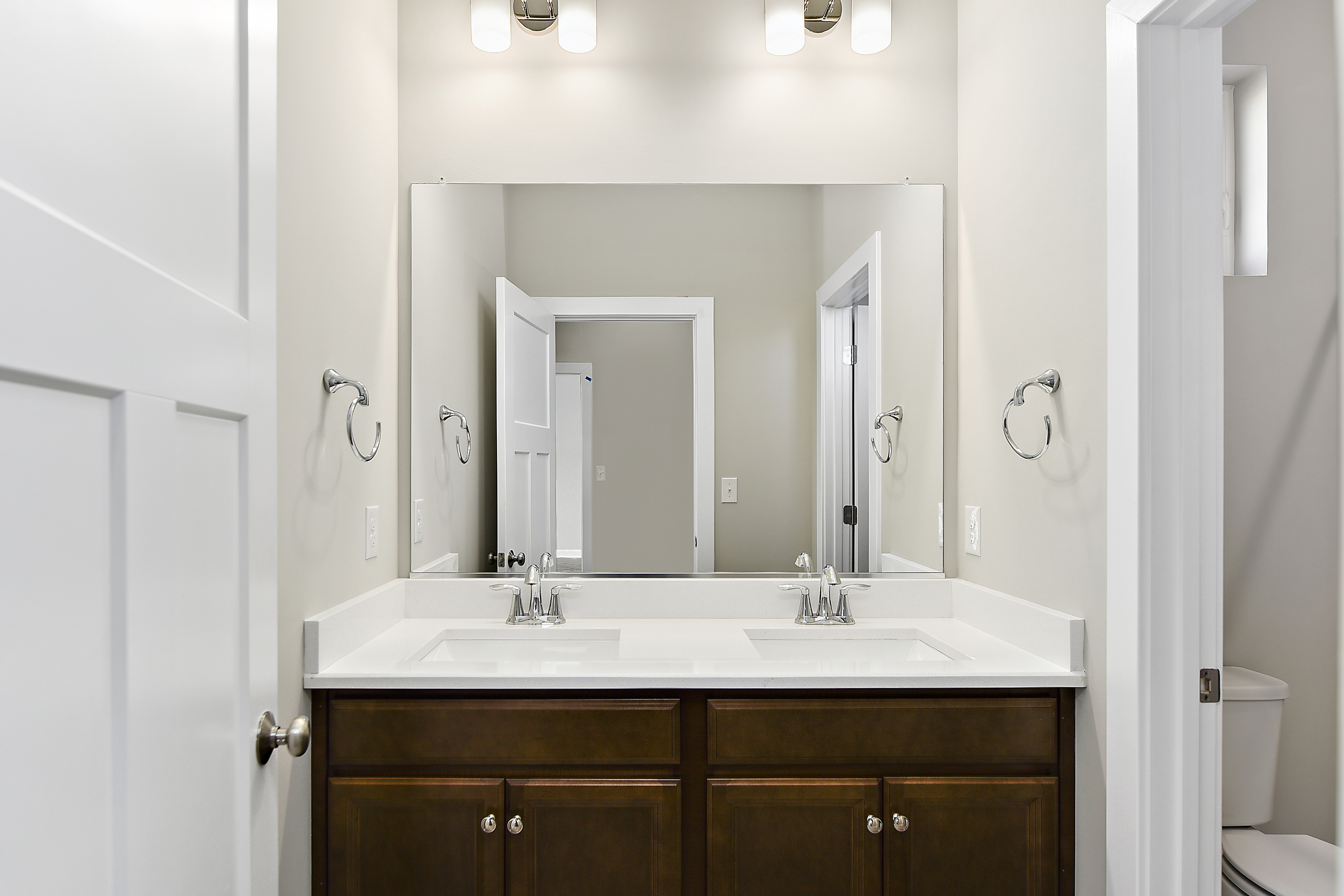 Brown cabinets and mirror in bathroom of Turnstone floorplan by Evergreene Homes