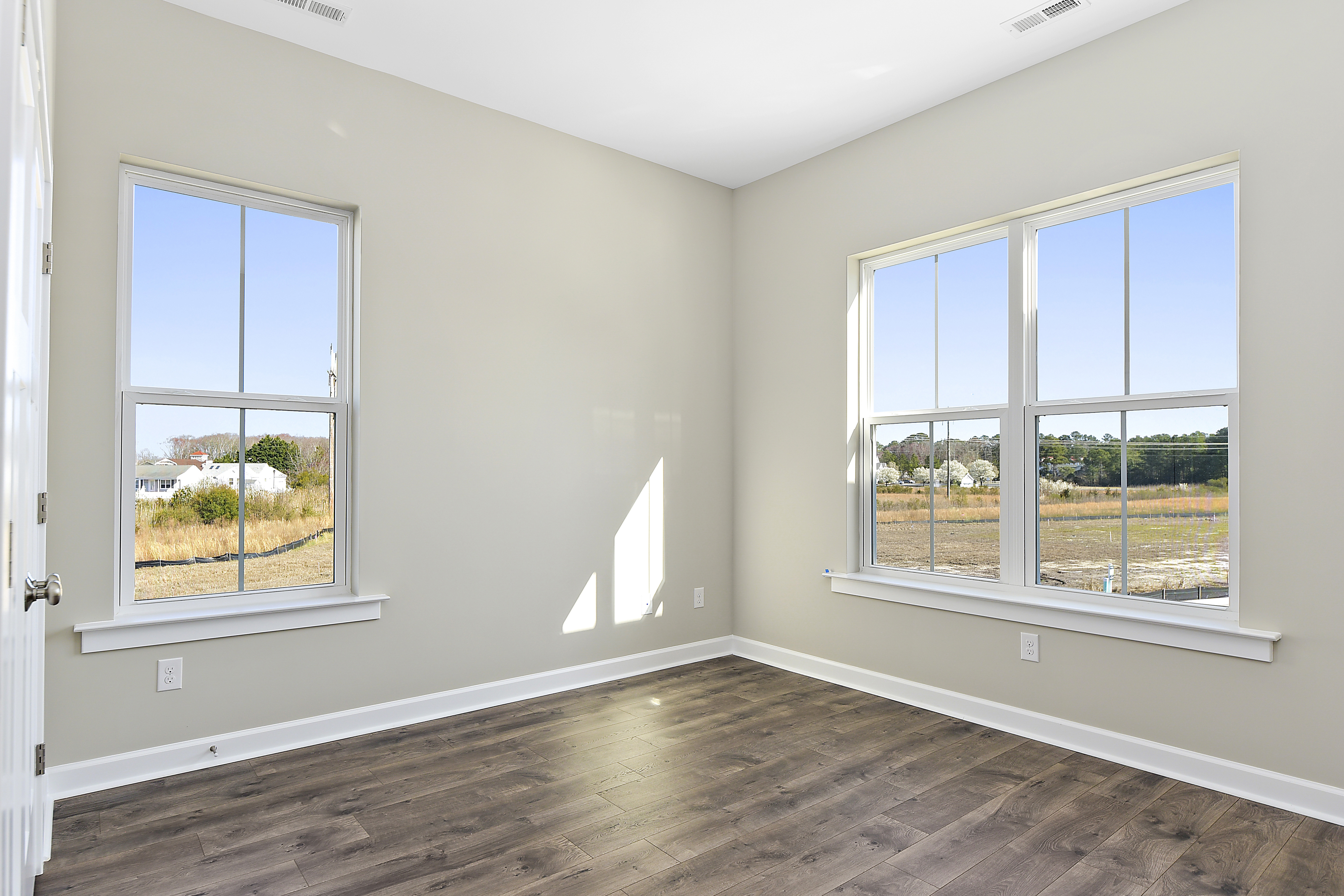 Empty bedroom with numerous windows and wooden floors